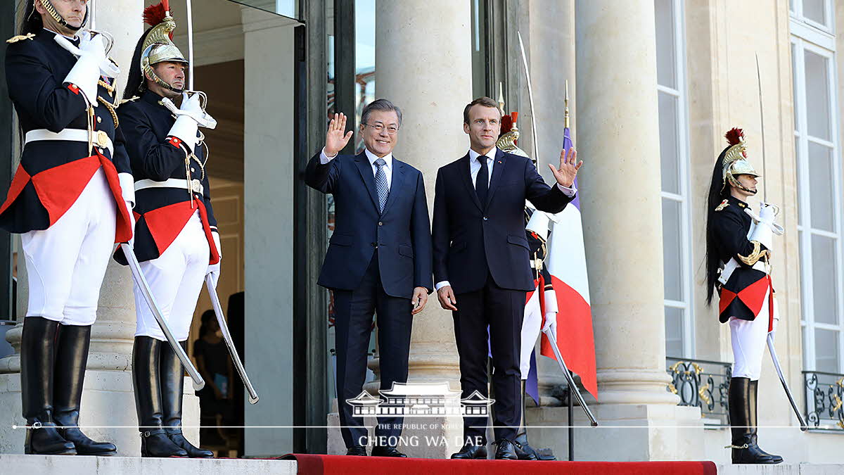 Being greeted by French President Emmanuel Macron upon arrival at the Élysée Palace in Paris