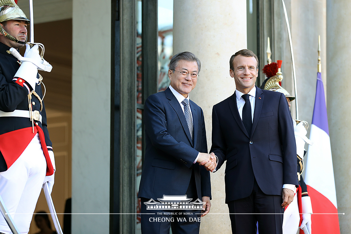 Being greeted by French President Emmanuel Macron upon arrival at the Élysée Palace in Paris 