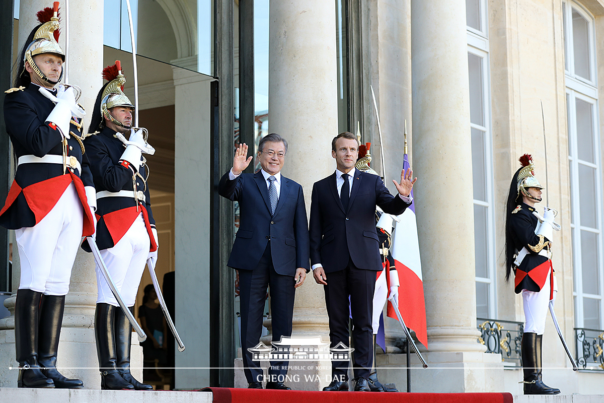 Being greeted by French President Emmanuel Macron upon arrival at the Élysée Palace in Paris 