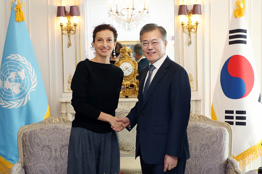 UNESCO Director-General Audrey Azoulay (left) and President Moon Jae-in shake hands before their meeting at the Hotel Plaza Athenee in Paris on Oct. 16.