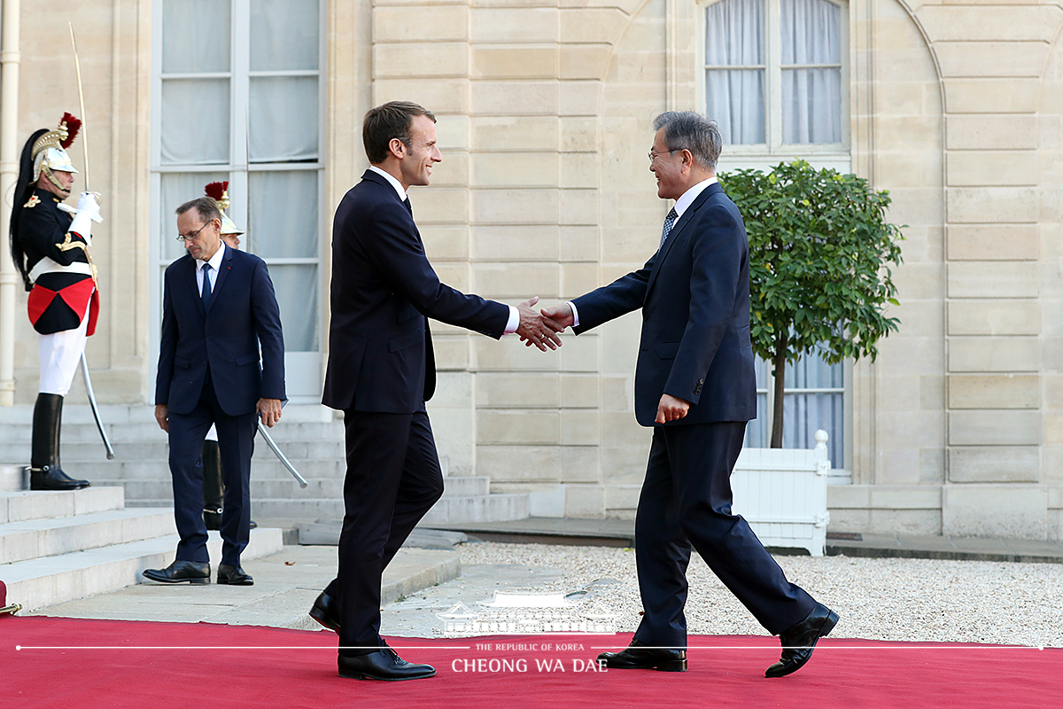 Being greeted by French President Emmanuel Macron upon arrival at the Élysée Palace in Paris 