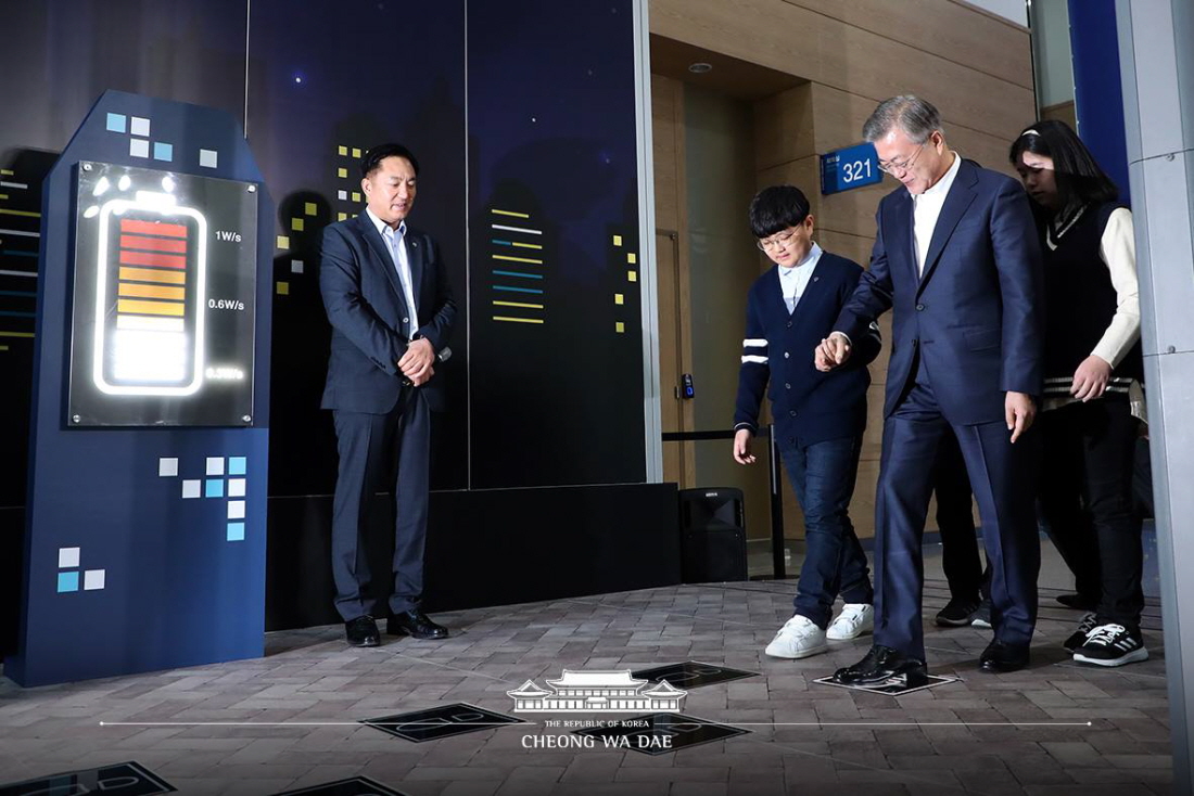 President Moon Jae-in on Feb. 13 visited the Busan Exhibition and Convention Center (BEXCO) to see a presentation on the Busan Smart City Innovative Strategy. He is seen here trying a high-tech floor designed by the Korean company HNJ that transforms kinetic energy into electricity when users step on the tiles with footprints.