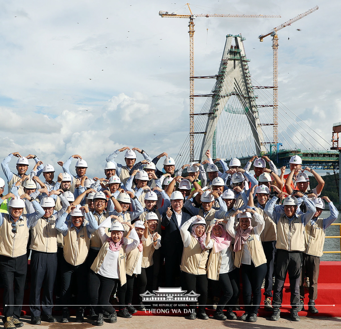 President Moon Jae-in on March 11 takes a photo with workers at the construction site of Temburong Bridge in Brunei. (Cheong Wa Dae)