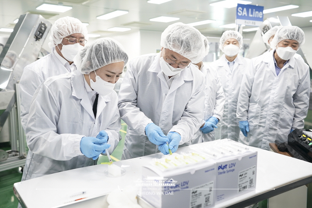 President Moon Jae-in (center) on Feb. 18 inspects low dead space syringes on a production line of the medical device manufacturer Poonglim Pharmatech in Gunsan, Jeollabuk-do Province. 