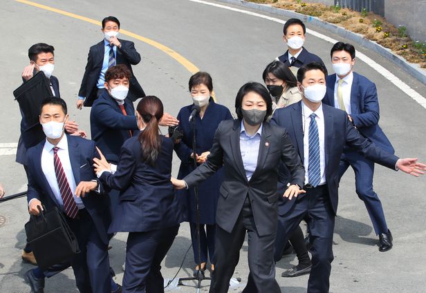 지난달 24일 대구 달성군 박근혜 전 대통령 사저 앞에서 소주병이 날아들자 경호원들이 박 전 대통령을 몸으로 에워싸며 엄호하고 있다.